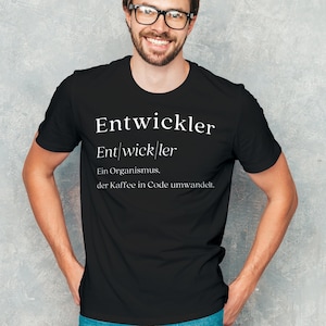 Könnte beinhalten: Ein schwarzes T-Shirt mit weißem Text, der "Entwickler Ent|wick|ler Ein Organismus, der Kaffee in Code umwandelt." lautet.