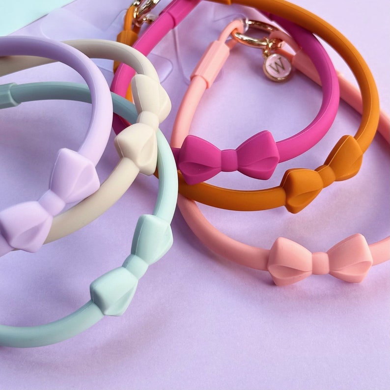May include: Five silicone bracelets with bow accents in various colours, including light blue, cream, pink, orange and magenta.