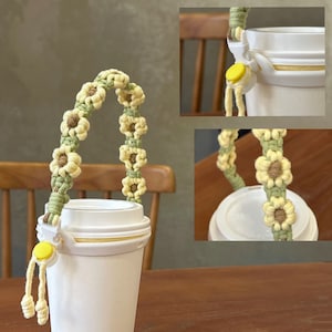May include: A white to-go cup with a yellow and green crocheted sunflower handle. The handle is attached to the cup with a yellow plastic clip.