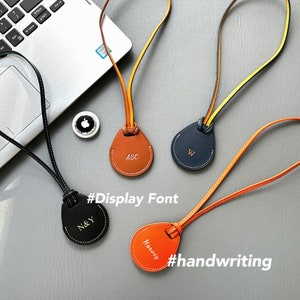 Puede incluir: Cuatro llaveros de cuero con correas de cuero de diferentes colores y etiquetas redondas de cuero. Las etiquetas están personalizadas con las letras "ABC", "W", "N&Y" y "Harvey" en diferentes fuentes. El texto "#Display Font" y "#handwriting" está escrito debajo de los llaveros.