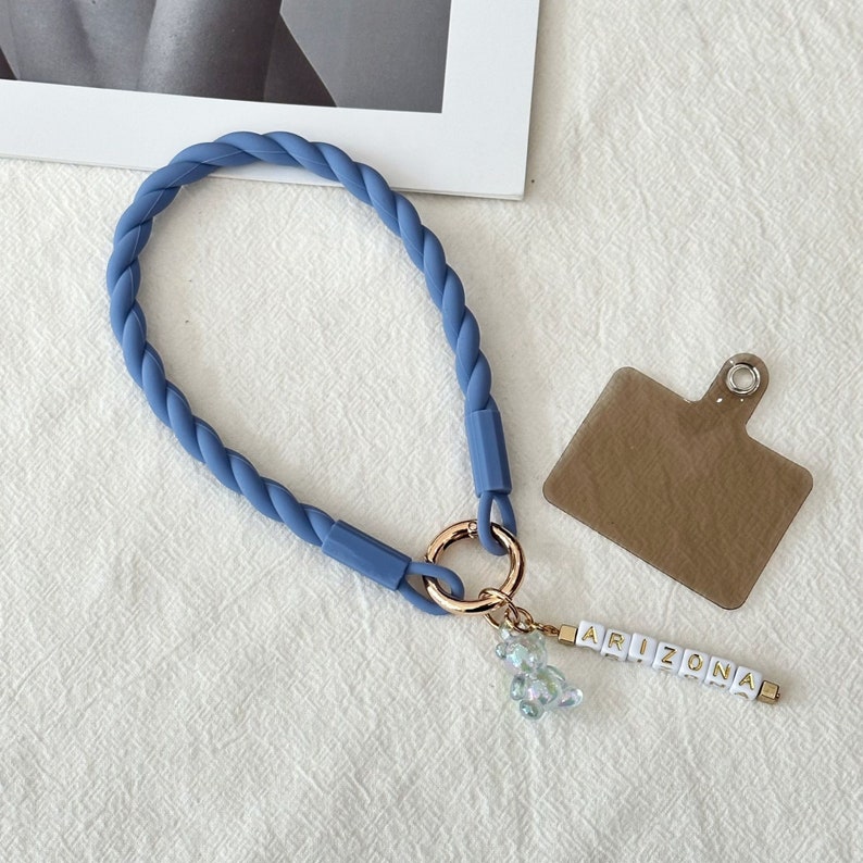 May include: A blue rope keychain with a gold ring, a clear beaded charm, and a white letter charm spelling "ARIZONA".