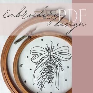 Op de afbeelding: Een borduurring met een voltooid ontwerp met een strik en takjes, met de tekst "Embroidery PDF design". Het ontwerp is zwart op een witte achtergrond, met houten ringen.