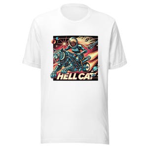 May include: White t-shirt featuring a vibrant graphic of a woman in a space suit riding a robotic tiger-motorcycle through space. The text "HELL CAT" is displayed in bold letters below the tiger.