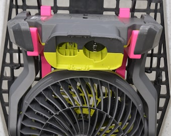 Può includere: Una ventola nera con una cornice gialla e verde fissata a una gabbia di metallo grigia. La ventola è etichettata "ONE" ed è montata all'interno di una cassa di plastica bianca. La cassa ha un motivo a griglia nera e il testo "Ruff Land Performance Kennels" è stampato sulla parte superiore.