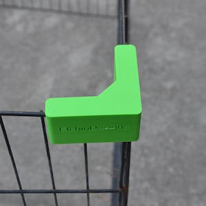 Könnte beinhalten: Ein hellgrüner, rechteckiger Eckenschutz aus Kunststoff für einen Metallkäfig. Der Eckenschutz hat den Text "Eichhorn Design" aufgedruckt.