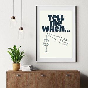 May include: A white framed print with a black and white illustration of a wine bottle pouring into a glass. The text "TELL me when..." is in bold blue letters.