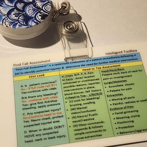 May include: A retractable badge reel with a blue and white patterned design, a clear plastic strap, and a card with medical assessment information. The card includes text about post-fall assessment and head-to-toe evaluation.