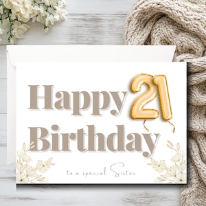 May include: A white birthday card with the words "Happy Birthday" in taupe. The number "21" is a gold balloon. The card reads "to a special Sister" with floral accents.