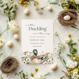 May include: A baby shower invitation with a watercolor illustration of a duckling in a nest of flowers. The text reads "a little Duckling is on the way". The invitation includes the date, time, and location of the shower.