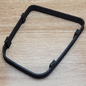 Könnte beinhalten: Schwarzer Kunststoffrahmen mit abgerundeten Ecken. Der Rahmen ist für die Aufnahme eines kleinen Objekts wie eines Telefons oder Tablets konzipiert.