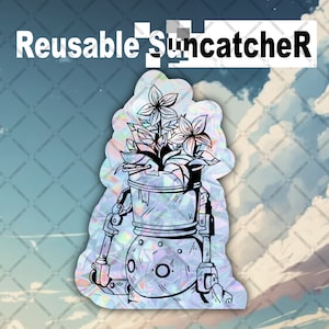 May include: A holographic suncatcher with a robot design holding flowers. The suncatcher has the words "Reusable Suncatcher" at the top. The robot has a round body and arms and legs. The flowers have five petals.