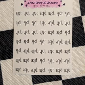 May include: A white sticker sheet with the text "appt." repeated multiple times. The sticker sheet has the text "ALMOST ROCKSTAR CREATIONS appt.- font ten" at the top. The background is a black and white checkered pattern.