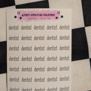 May include: A white sticker with the text "dentist" repeated multiple times in a black, sans-serif font. The sticker also includes the text "ALMOST ROCKSTAR CREATIONS dentist - font ten" in a pink banner with star accents.
