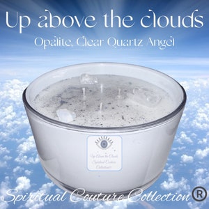Op de afbeelding: Een grote, witte kaars in een transparante glazen container, versierd met heldere kwartskristallen. De kaars heeft drie lonten. De tekst luidt "Up above the clouds" en "Spiritual Couture Collection".
