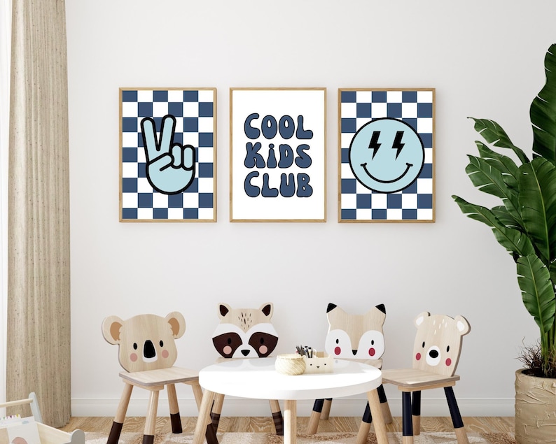 May include: Three blue and white checkered prints with a peace sign, the words "Cool Kids Club", and a smiley face with lightning bolts. The prints are hanging on a white wall above a table with four wooden animal chairs.