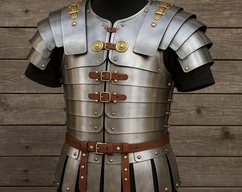 May include: A silver-colored Roman-style cuirass, displayed on a black mannequin. The armor features layered metal plates, leather straps, and brass accents. The design includes shoulder guards and a waist belt, showcasing historical craftsmanship.