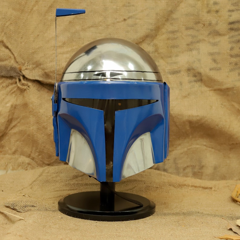 May include: A blue and silver helmet with a black base. The helmet has a shiny silver dome and a blue faceplate with silver accents. A small antenna extends from the top. The helmet is a prop or collectible.