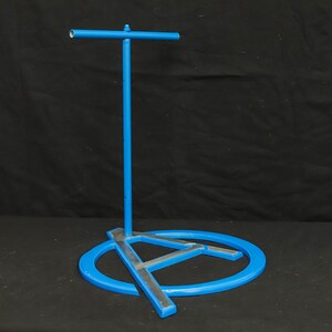 May include: A blue metal stand with a circular base and a crossbar. The base is shaped like a stylised letter A.