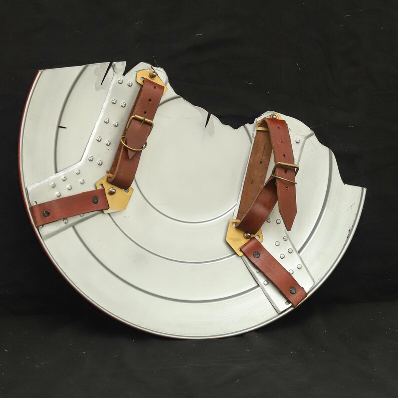 May include: The back of a silver Captain America shield with brown leather straps and brass buckles.