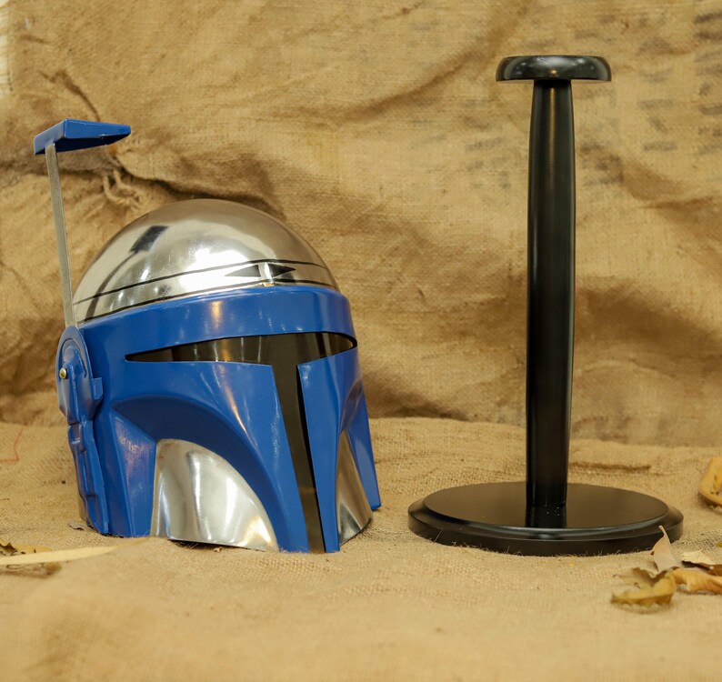 May include: A blue and silver helmet with a black visor and a matching black stand. The helmet has a unique design with a silver dome and blue faceplate. The stand is black and round.