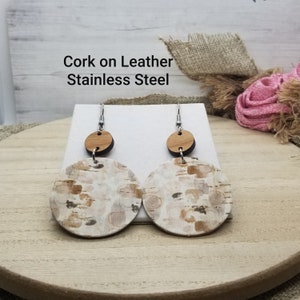 May include: Cork and leather earrings with a white and brown patterned design. The earrings are attached to stainless steel hooks.