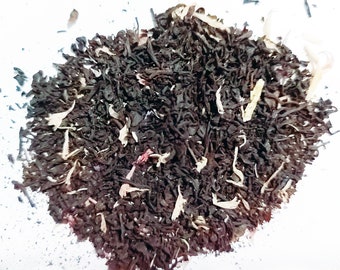 May include: A close-up of a blend of black tea leaves, dried fruit pieces, and flower petals. The tea is a mix of brown, black, and white colors.