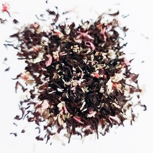 May include: A close-up of a blend of black tea leaves with pink and white flower petals.