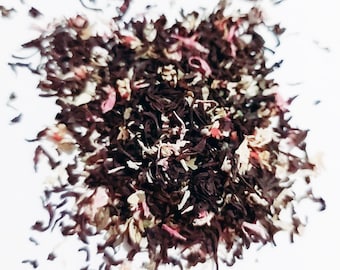 May include: A close-up of a blend of black tea leaves with pink and white flower petals.