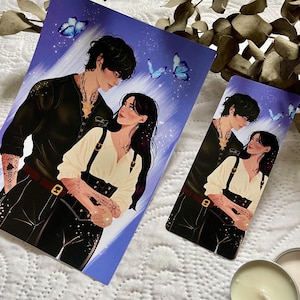 Può includere: Una coppia in una posa romantica con farfalle blu sullo sfondo. La donna indossa una camicia bianca con un corsetto nero e l'uomo indossa una camicia nera con una collana d'argento. L'immagine è stampata su uno sfondo bianco.