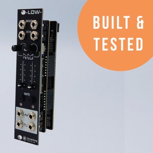 May include: A black and white electronic music module with the text "O-LOW-" and "Something Modular" printed on it. The module has knobs, jacks, and a switch. The text "BUILT & TESTED" is printed on a large orange circle in the background.