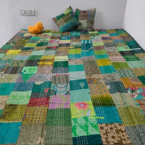 May include: A patchwork quilt in shades of green, teal, and brown, with a variety of fabric patterns. Two decorative pillows and a small yellow stuffed animal are on top of the quilt. The quilt is on a bed.