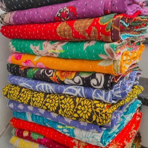 Peut inclure: Une pile de courtepointes kantha color&eacute;es avec des motifs floraux. Les courtepointes sont faites de saris recycl&eacute;s et sont cousues &agrave; la main. Les courtepointes sont un choix populaire pour la d&eacute;coration de la maison et sont connues pour leurs designs uniques et leur durabilit&eacute;.