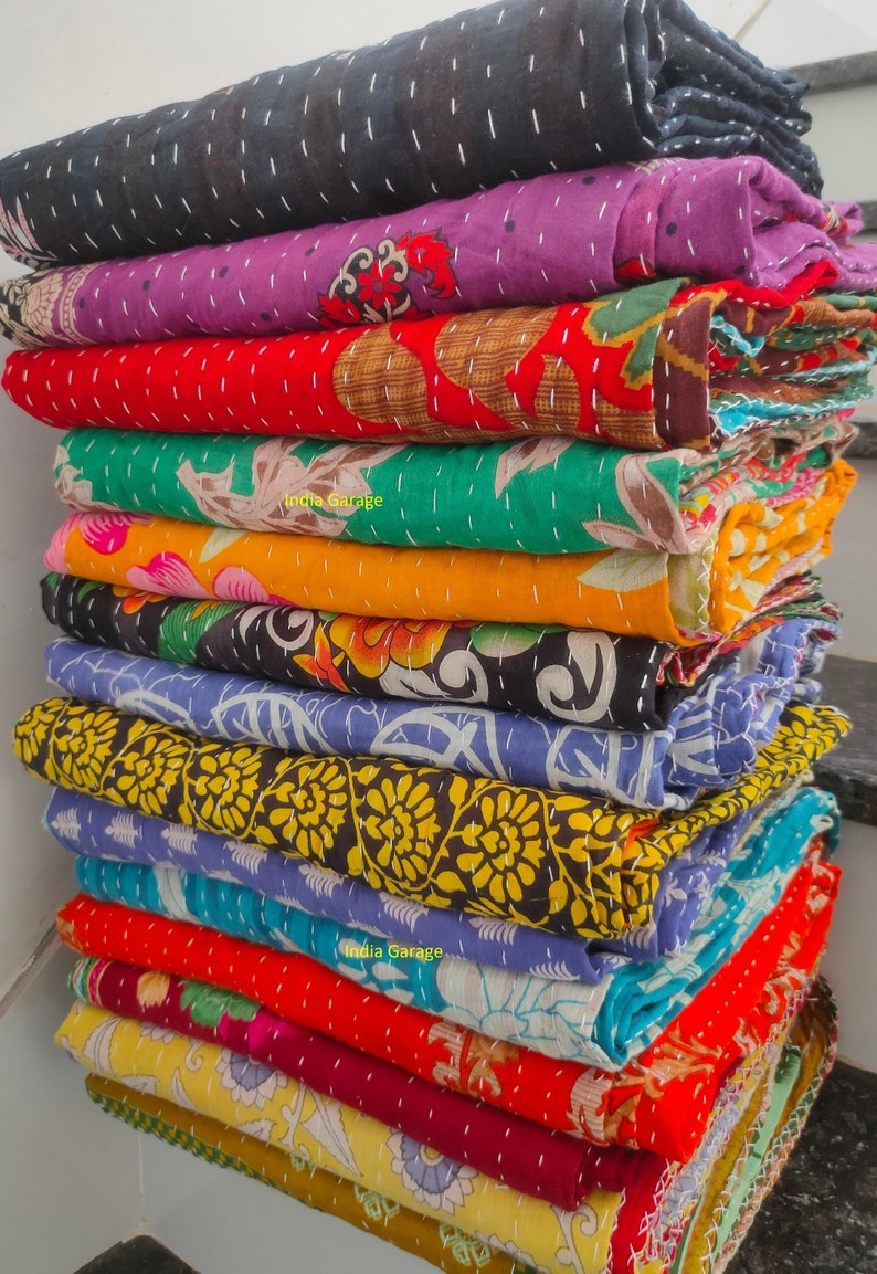 Peut inclure: Une pile de courtepointes kantha color&eacute;es avec des motifs floraux. Les courtepointes sont faites de saris recycl&eacute;s et sont cousues &agrave; la main. Les courtepointes sont un choix populaire pour la d&eacute;coration de la maison et sont connues pour leurs designs uniques et leur durabilit&eacute;.