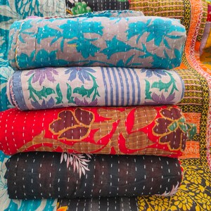Peut inclure: Une pile de quatre quilts kantha de diff&eacute;rentes couleurs et motifs, notamment bleu, rouge, noir et blanc. Les quilts sont en coton et pr&eacute;sentent un design cousu &agrave; la main.