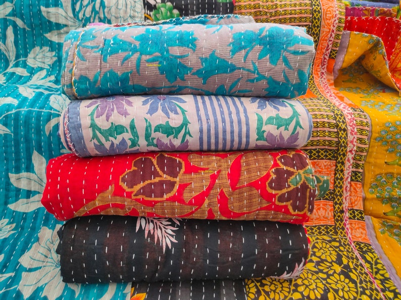 Peut inclure: Une pile de quatre quilts kantha de diff&eacute;rentes couleurs et motifs, notamment bleu, rouge, noir et blanc. Les quilts sont en coton et pr&eacute;sentent un design cousu &agrave; la main.