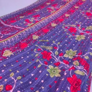 Peut inclure: Une courtepointe kantha bleue avec un motif floral dans des tons de rouge, vert et blanc. La courtepointe est cousue &agrave; la main et pr&eacute;sente un design indien traditionnel.