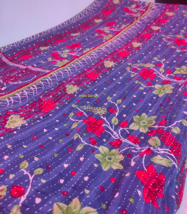 Peut inclure: Une courtepointe kantha bleue avec un motif floral dans des tons de rouge, vert et blanc. La courtepointe est cousue &agrave; la main et pr&eacute;sente un design indien traditionnel.