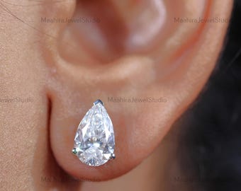 May include: A pair of pear-shaped diamond stud earrings. The earrings are set in a silver metal setting.