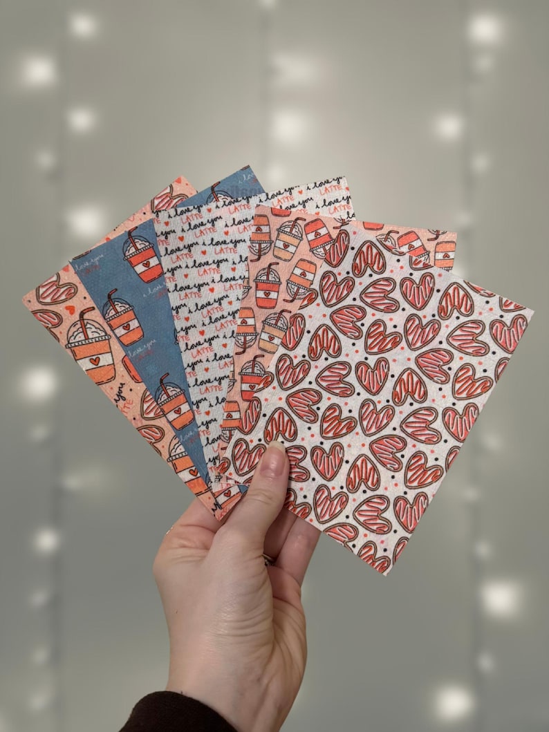 Puede incluir: Un conjunto de cuatro cuadrados de tela estampada con un dise&ntilde;o de taza de caf&eacute; con el texto "I love you latte" y un dise&ntilde;o de coraz&oacute;n con rayas rojas y blancas.