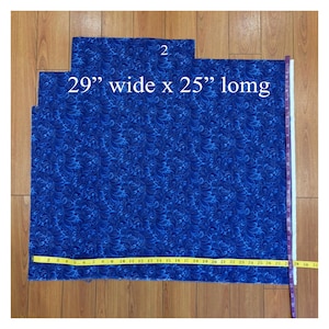 May include: A piece of blue fabric with a swirling pattern, measuring 29 inches wide and 25 inches long. The number "2" is visible in the top center. A yellow measuring tape is laid across the fabric.