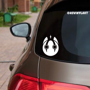 May include: White vinyl sticker of a stylized face with large eyes and a star on top. The sticker is on the back window of a car. The text "@ASVINYLART" is in the upper right corner of the image.