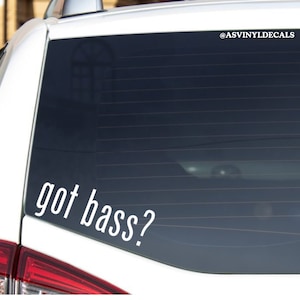 May include: White vinyl decal sticker with the text "got bass?" on a black car window. The sticker is placed on the lower right corner of the window. The decal is for sale on Etsy.