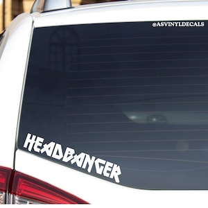 May include: White vinyl decal with the text "HEADBANGER" on a black car window. The decal is in a stylized font with sharp angles.