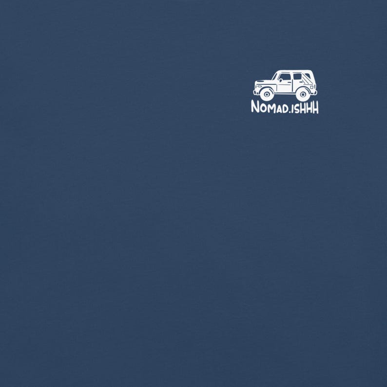 May include: A navy blue t-shirt featuring a white graphic of a vintage SUV and the text "Nomad.ISHHH". The design is simple and clean, perfect for outdoor enthusiasts and travel lovers.
