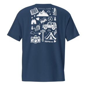 May include: Dark blue t-shirt with a white graphic design. The design includes camping and travel-themed illustrations such as a camera, tent, mountains, and the text "NATIONAL PARKS" and "NOMAD.ISH".