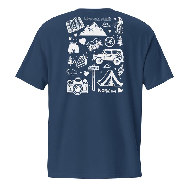 May include: Dark blue t-shirt with a white graphic design. The design includes camping and travel-themed illustrations such as a camera, tent, mountains, and the text "NATIONAL PARKS" and "NOMAD.ISH".