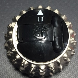 May include: A silver typewriter ball with a black plastic cover. The cover has a white triangle pointing upwards and the number 10 printed on it. The cover also has a black plastic tab with the letters GP printed on it.