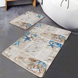 May include: A set of two bath mats featuring a beach theme. The mats are beige with blue starfish and seashells. The mats are positioned on a grey tiled floor in a bathroom.