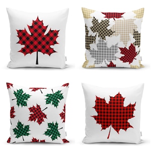 Puede incluir: Cuatro cojines blancos con diseños de hojas de arce. Dos cojines presentan hojas de cuadros rojos y negros. Uno tiene un patrón de hojas de pata de gallo rojas, negras y beige. El último tiene un patrón de hojas de cuadros rojos y verdes.