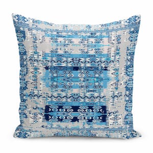 May include: A square throw pillow featuring a repeating geometric pattern in shades of navy blue, light blue, and white. The design includes horizontal bands of intricate shapes and distressed textures on a light gray background.